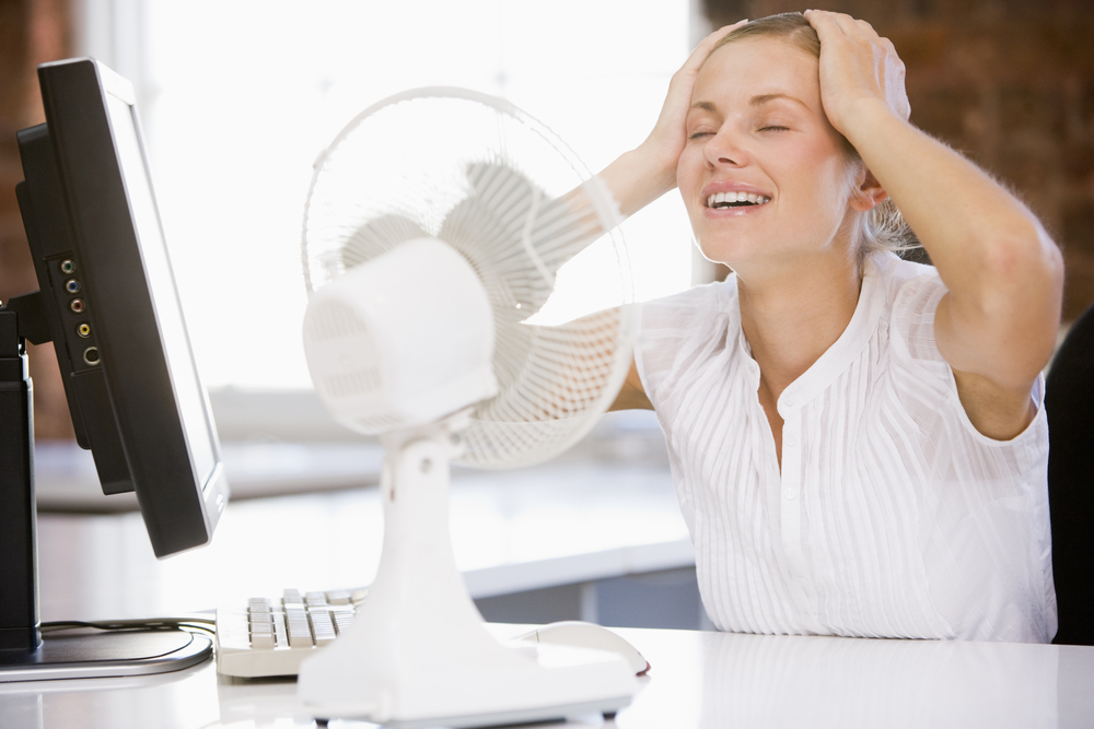 A woman cools off by her fan