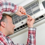 A man repairs his AC unit